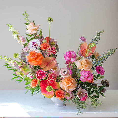 A tropical coloured arrangement made with bright orange and pink flowers.